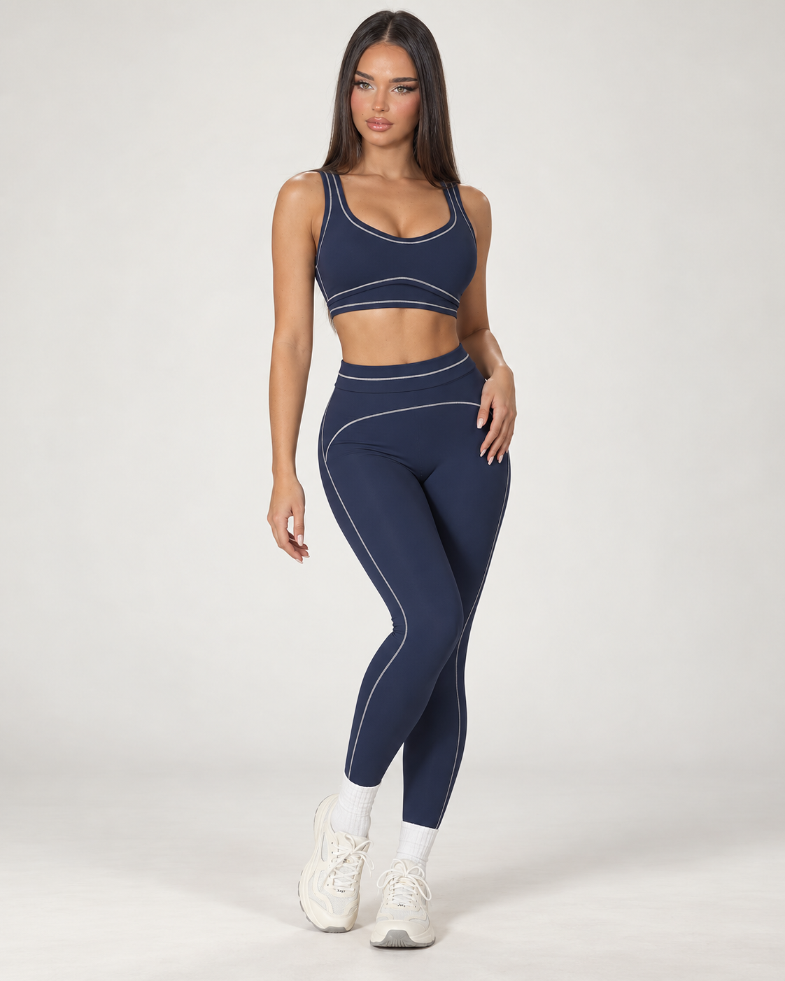 navy blue women’s gym outfit with a fitted sports bra and high waisted flared activewear leggings, detailed with curved contrast seams and white piping for a body contouring workout, training and athleisure look