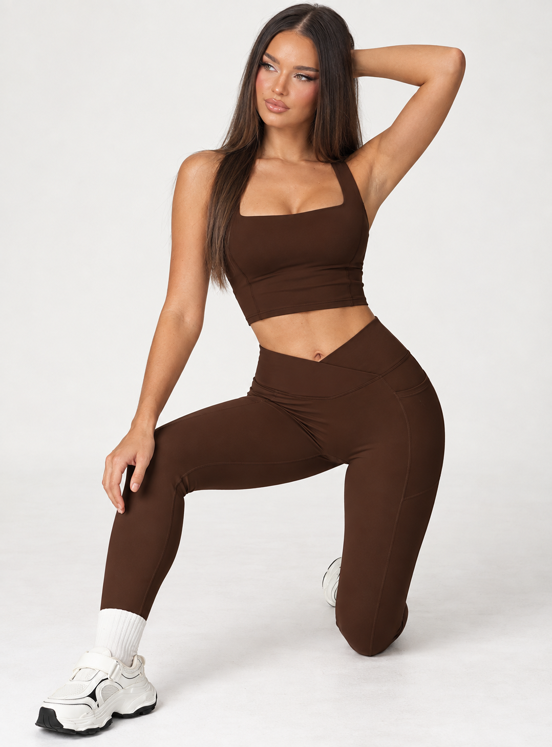 Chocolate brown women’s workout activewear set featuring a body contouring sleeveless crop top and high rise crossover waist leggings, styled as a feminine coordinated gym outfit for exercise and training