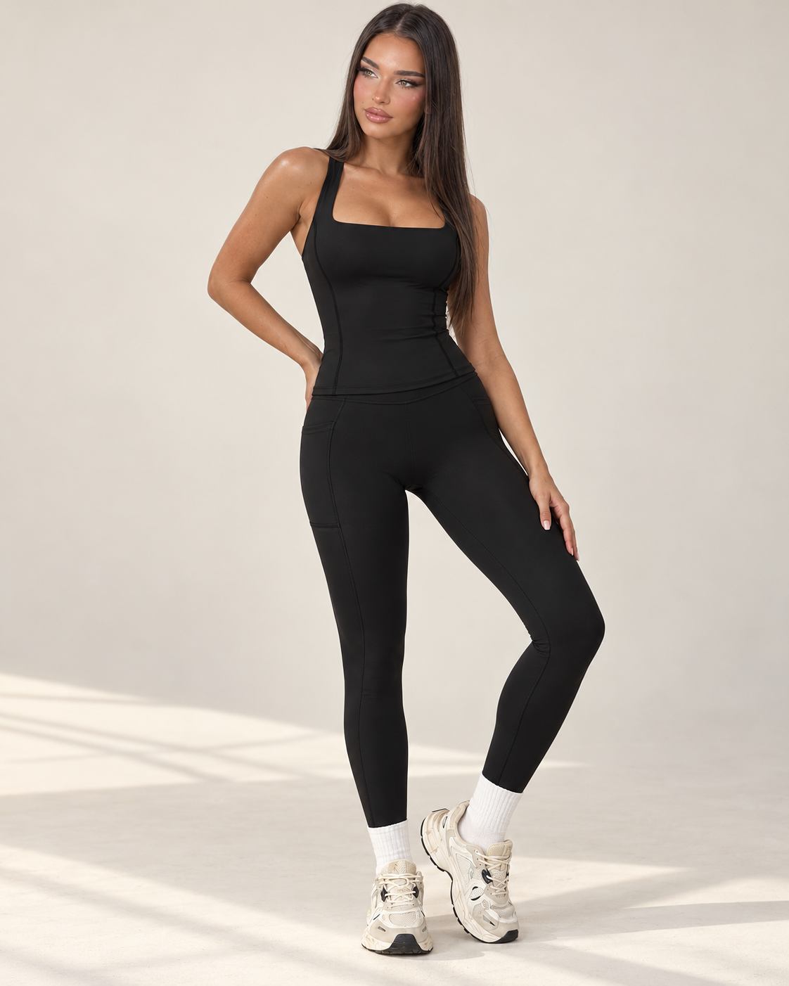 black women’s activewear co ord with a fitted sleeveless square neck training top and full length high waisted sculpting leggings with crossover V waistband, a premium ERAFITT workout and athleisure set