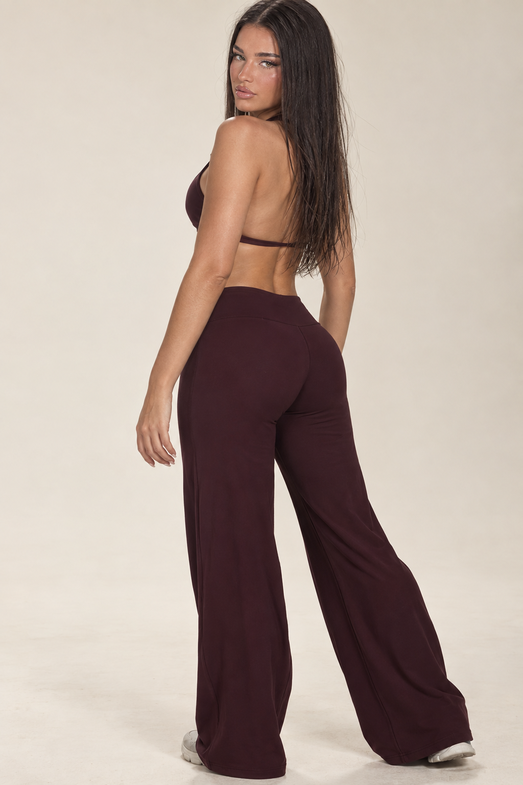 Deep burgundy women’s Pilates set featuring an open back strappy sports bra and high waist wide leg yoga pants