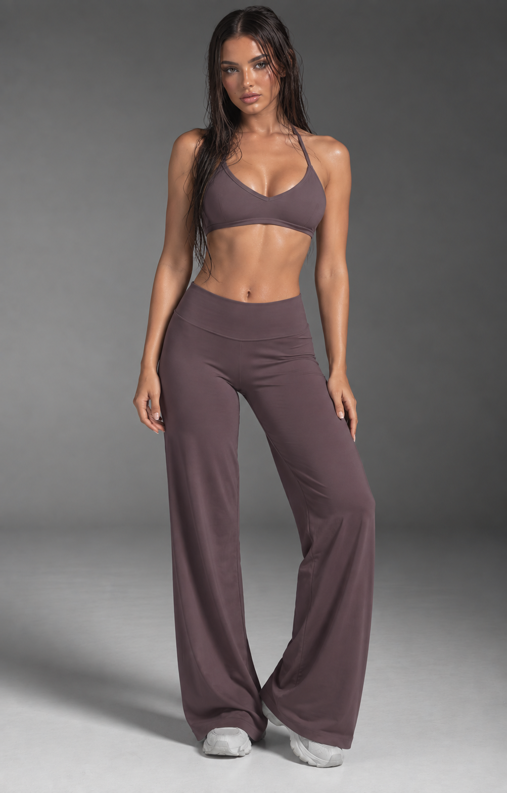 Deep plum women’s studio outfit featuring a minimalist open back crop top and relaxed wide leg performance pants