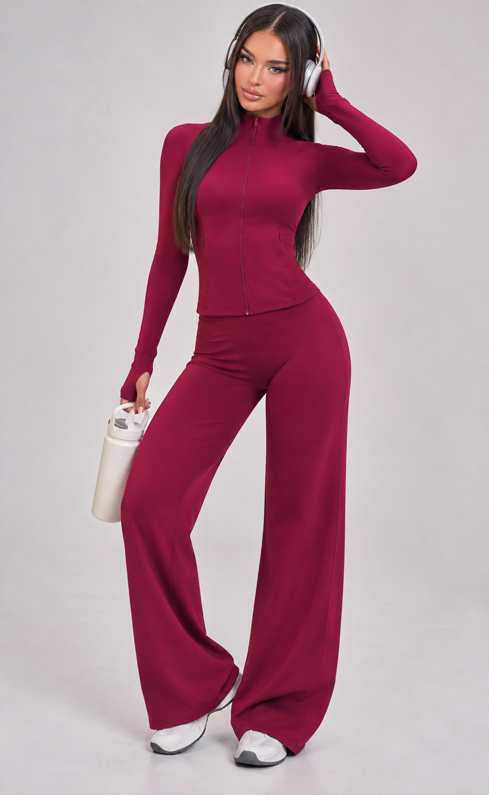 Women’s raspberry red Pilates outfit with sculpting long sleeve performance jacket and flowing high rise wide leg activewear pants