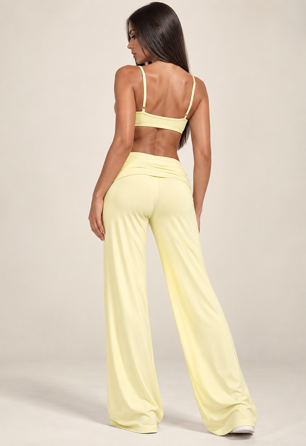 Butter yellow women's two-piece activewear set featuring a layered sports bra with dark brown contrast detailing and matching high-waisted wide-leg trousers.