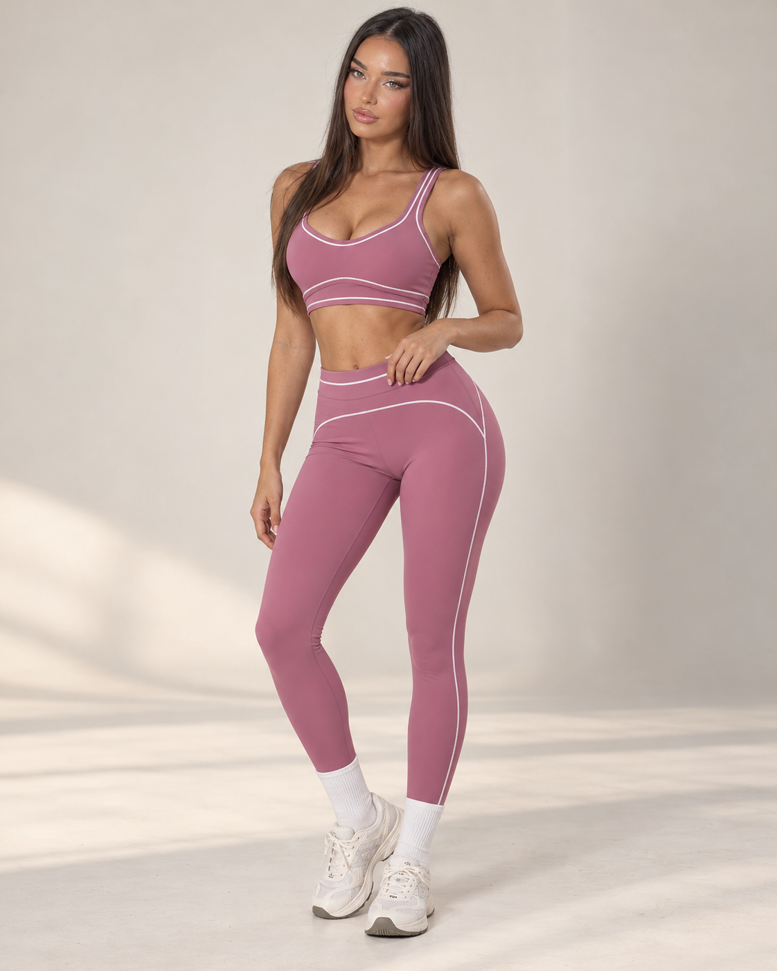pink women’s gym outfit with a fitted sports bra and high waisted flared activewear leggings, detailed with curved contrast seams and white piping for a body contouring workout, training and athleisure look