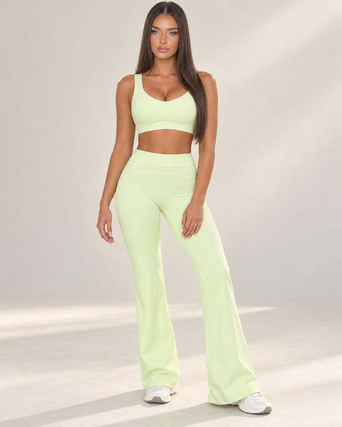 pistachio green women’s gym outfit with a fitted sports bra and high waisted flared activewear leggings, detailed with curved contrast seams and white piping for a body contouring workout, training and athleisure look