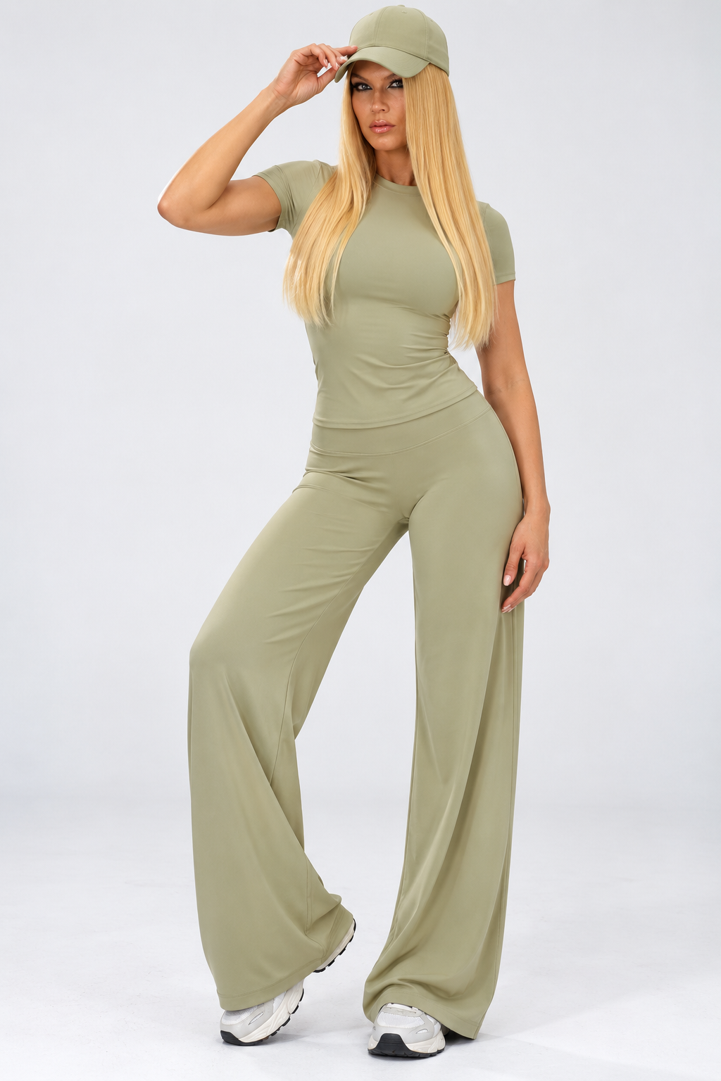 Sage green women's tennis activewear set with a fitted V-neck crop top and high-waisted wide-leg trousers, styled with a tennis racket on court.