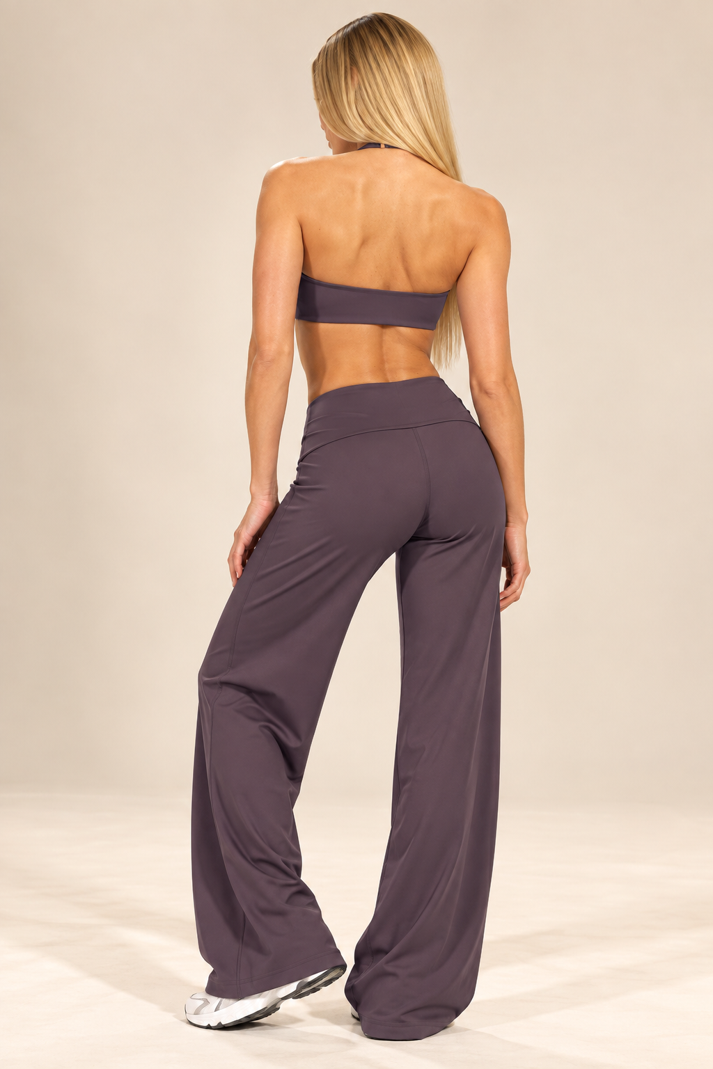 Women's muted plum Pilates outfit featuring a minimal backless crop top, smooth high-rise waistband and flowing full-length flared pants.
