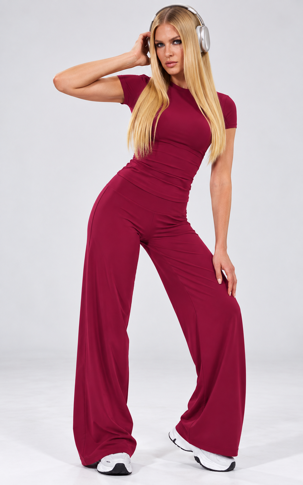 Full-length front view of a deep crimson two-piece sports set with a fitted short-sleeve top and relaxed wide-leg pants against a clean studio backdrop.