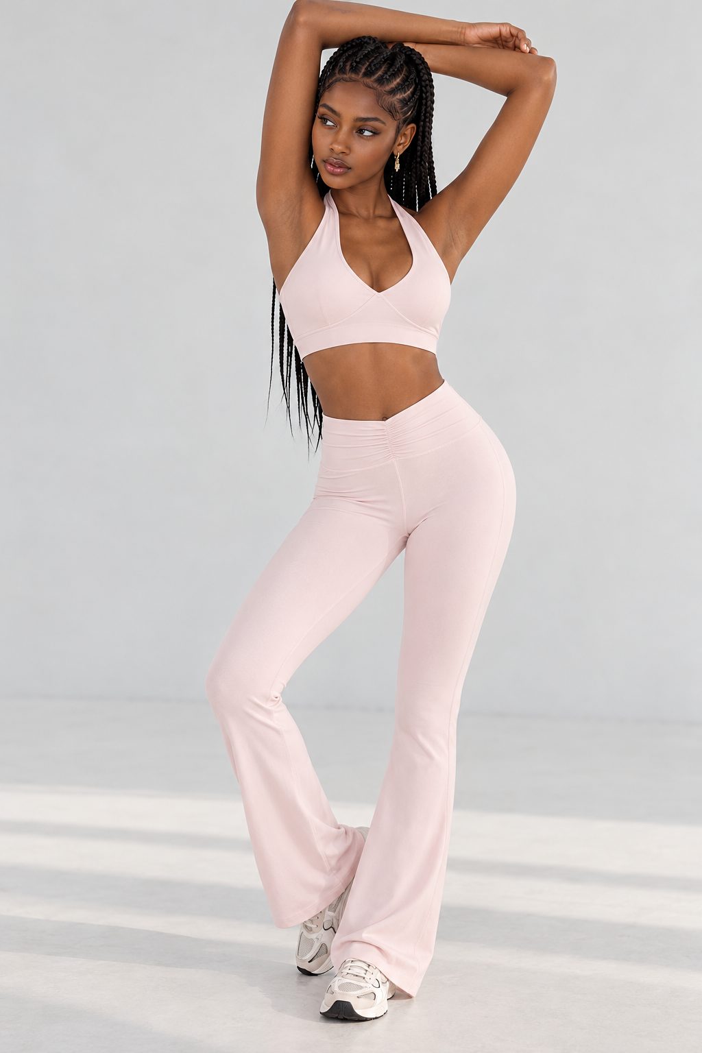 power pink women's yoga set featuring a fitted halter sports top, wide gathered waistband and gently flared athletic leggings, styled with chunky white trainers.