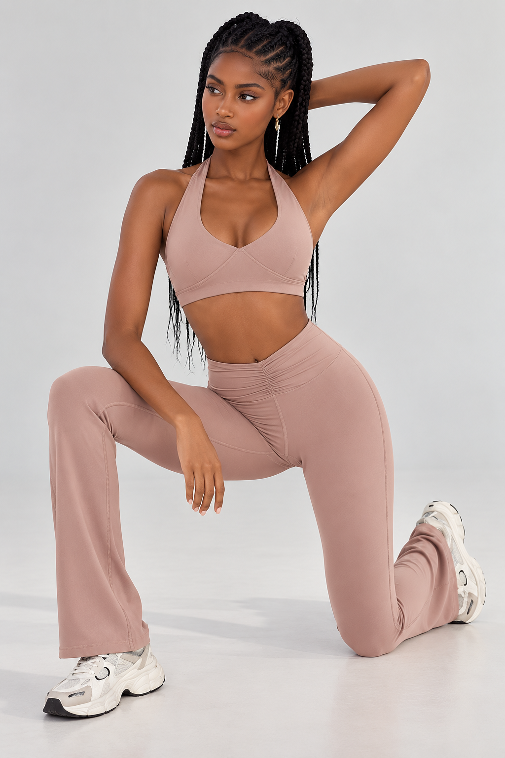 Dusty rose women's activewear set featuring a halter-neck sports bra with overlapping front panels, sculpted underbust seams and matching high-waisted flared leggings.