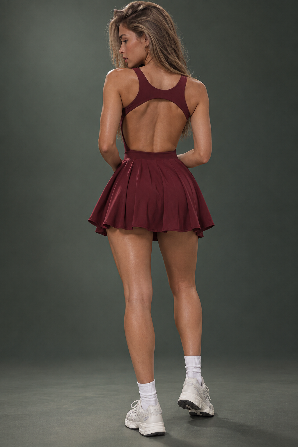 Rich burgundy women's tennis dress featuring a fitted scoop-neck bodice, wide shoulder straps and a pleated mini skirt with a distinctive V-shaped waistline.