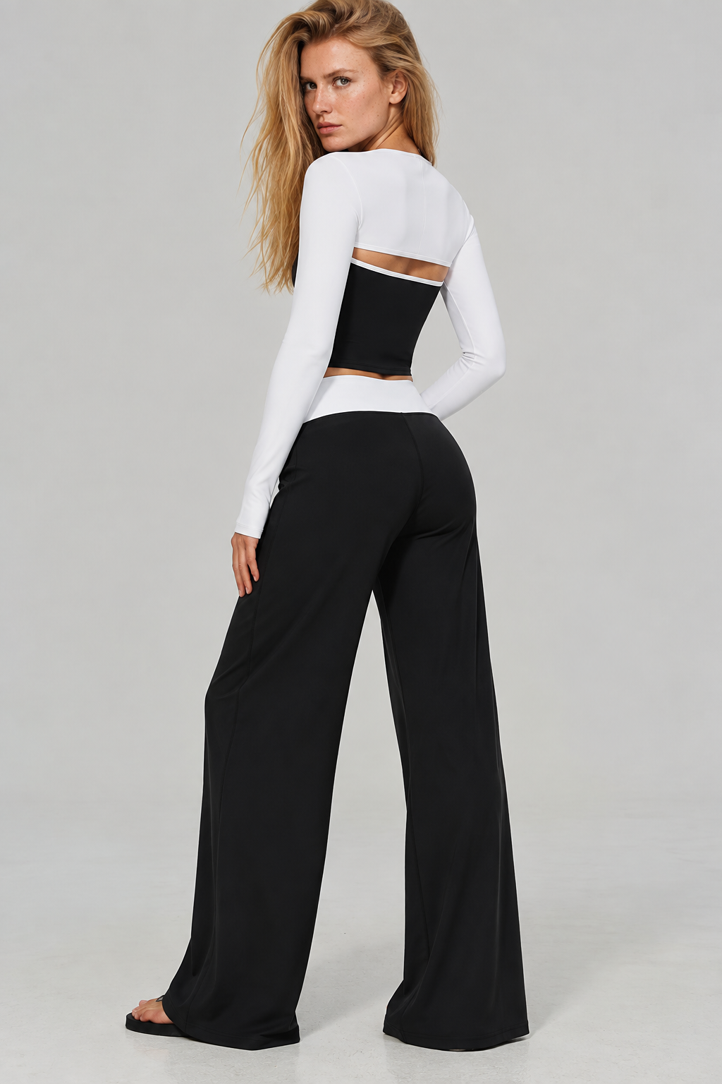 black & white women’s Pilates outfit featuring layered long sleeves, fitted contrast crop top and high waisted wide leg yoga trousers